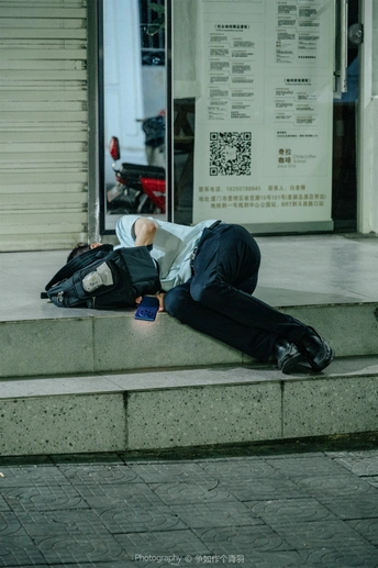 一个人在建筑物前的人行道上睡觉 人行道上躺着一个人。