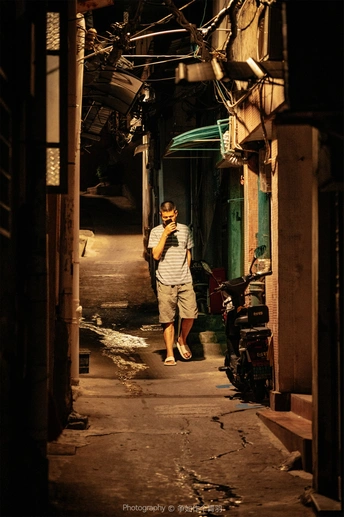 一个夜晚站在狭窄巷子里打电话的男人