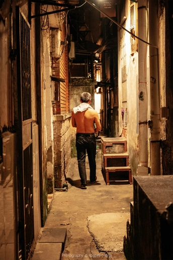 一个夜晚在狭窄的巷子里行走于老建筑之间的人