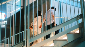 一个男子和一个女子在建筑物中走下楼梯 手牵着手。