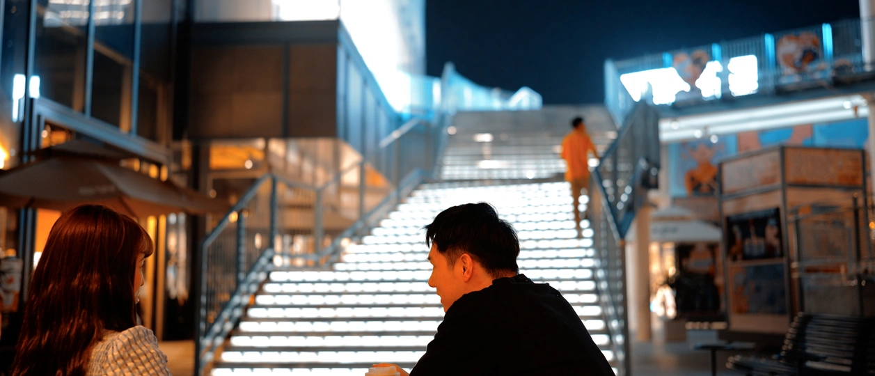 一个妇女在打电话 一个男子在建筑物楼梯上坐着 夜晚