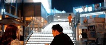 一个妇女在打电话 一个男子在建筑物楼梯上坐着 夜晚