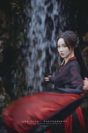 一位穿红裙子的女人在水帘洞前