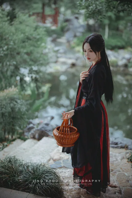 一位穿着黑色连衣裙的女士  carrying一个红色的篮子  standing next to a 