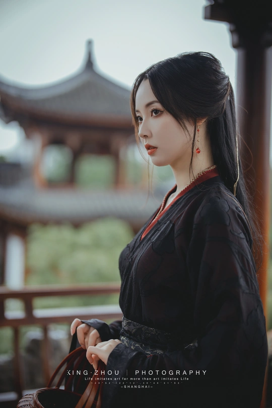 一位穿着黑色和服的年轻女子站在佛塔前