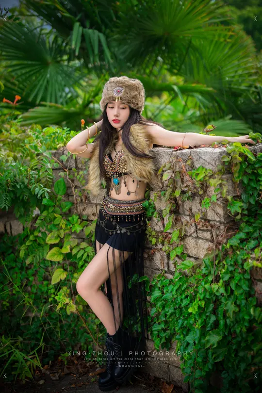 一位穿着 Costume 的美丽年轻女子在墙上长着常春藤的墙前摆姿势