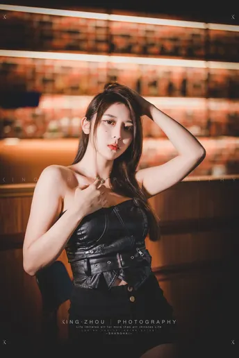 一个穿黑色连衣裙的女人在酒吧里摆姿势