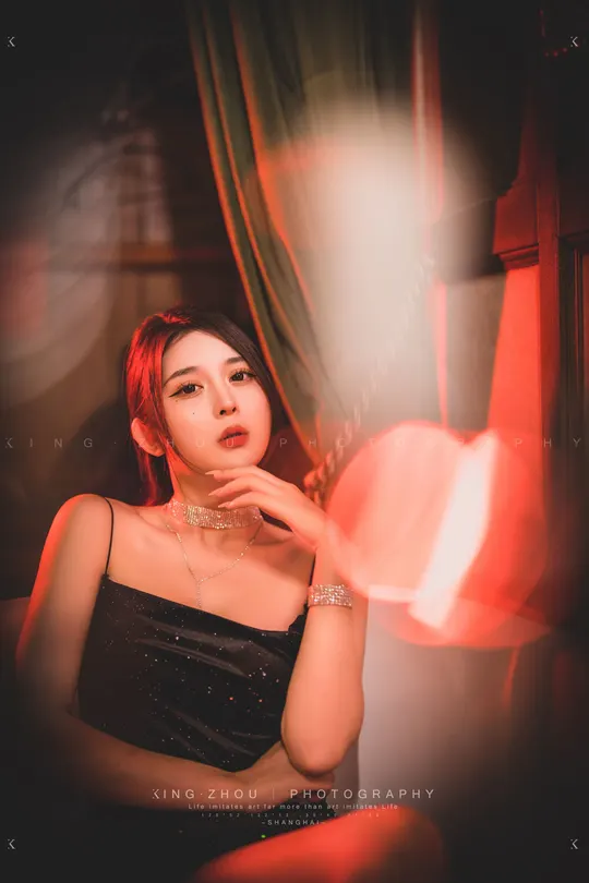 一个穿着黑色连衣裙的年轻女子坐在光线昏暗的房间里