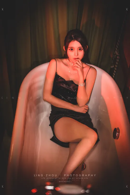 一个穿着黑色连衣裙的女孩坐在浴缸里的椅子上