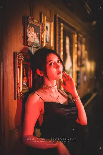 一个穿着黑色连衣裙的年轻女子在走廊里点了一支烟。