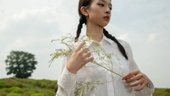 一位年轻女子站在田野中 手里拿着一株草的照片 免费照片