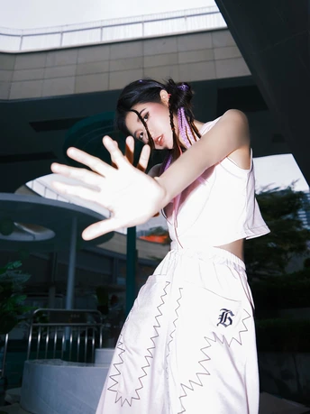 一位穿着白色连衣裙的年轻女子正在做“V”字手势。