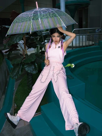 一个穿着粉红色睡衣的年轻女子站在楼梯上 手里拿着一把雨伞。
