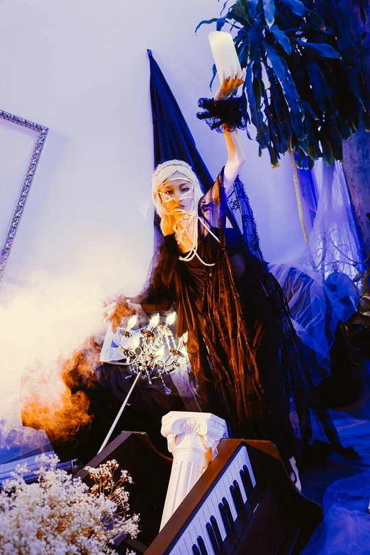 一个穿着 costume 的人 holding a candle next to a keyboar