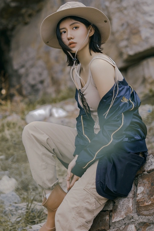 一位年轻女子戴着帽子坐在岩石上