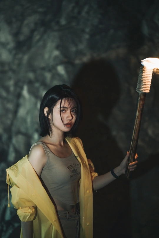 一位年轻女子在洞穴中手持黄色权杖 手中持有一盏点燃的火炬。