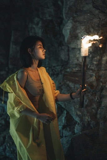 一个年轻女子在一个洞穴里拿着一个灯笼 手中有点燃的火焰 站在一个拿着点燃蜡烛的人的前面。