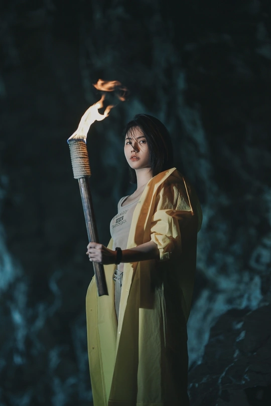 一位身着和服的女性手持点燃的蜡烛 站在一个洞穴里 手拿一支点燃的火把。