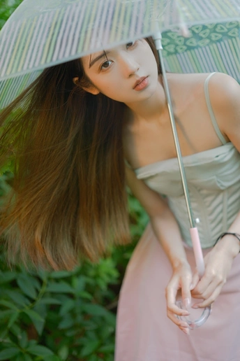 一位穿着粉红色连衣裙的年轻女子拿着条纹雨伞