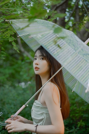 一位穿着绿色连衣裙的年轻女子拿着雨伞