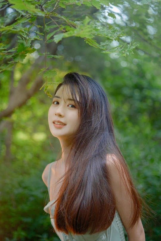 站在绿色森林中的长发年轻女子肖像