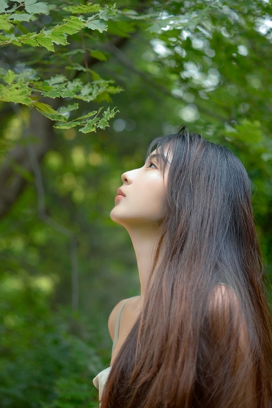 一位年轻女子在森林中穿过树丛仰望天空