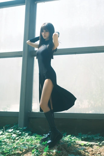 一位穿着黑色连衣裙和靴子的年轻女子站在窗户前