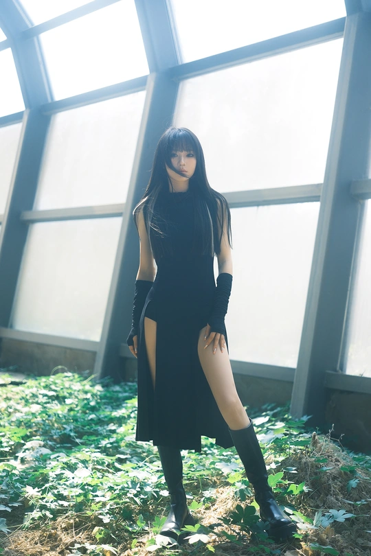 一位穿着黑色连衣裙和靴子的女性站在窗户前