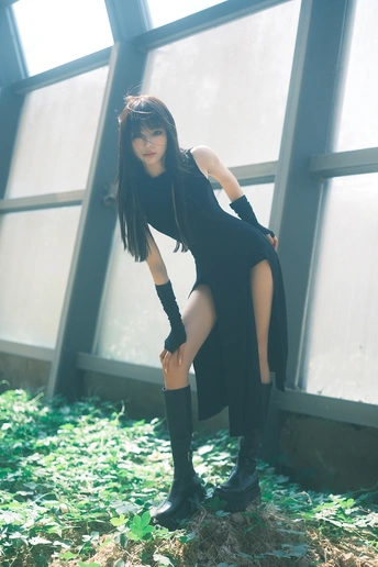 一位穿着黑色连衣裙和高筒靴的年轻女子站在窗户前