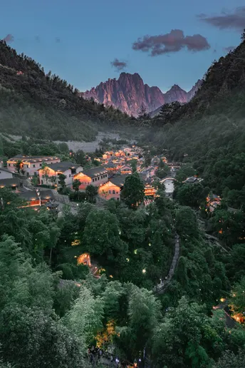 傍晚时分 一座城市在背景中熠熠生辉 山峦在远处 小镇在前方。