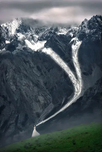 新人站在一个有山丘为背景的田野中