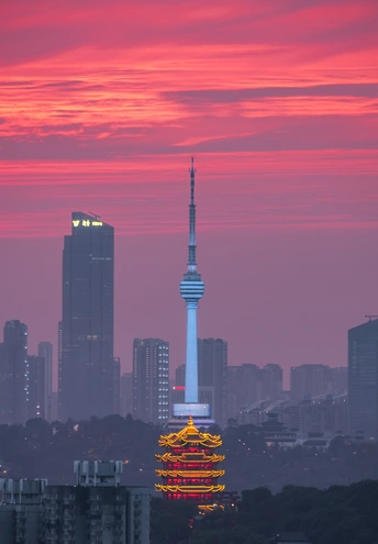 暮色或日落时分的城市天际线 前景是一座高塔 背景是其他建筑 天空是粉红色和红色的 