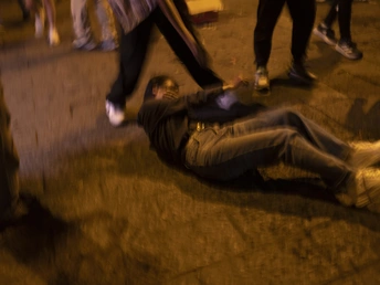 一个男子晚上躺在人行道上 周围有一群人。