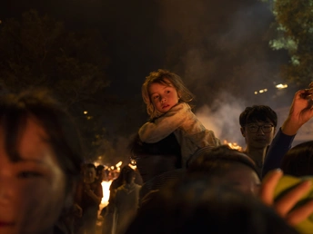 站在人群旁边举着蜡烛的女人