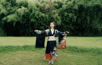 一位穿着日本传统和服的年轻女子站在田野中