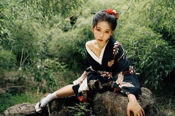 一位穿着日本传统和服的美女坐在岩石上