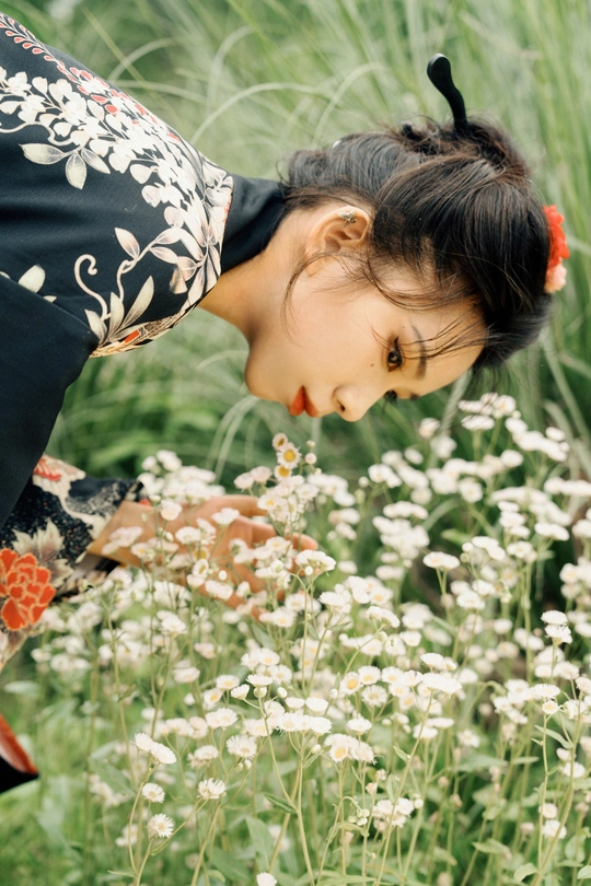 一位年轻女子在花田里闻着一朵小花