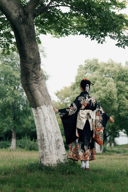 一位穿着传统服装的女性站在一棵树旁边