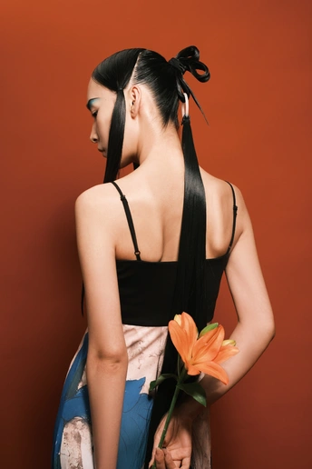 一位长发年轻女子穿着黑色连衣裙手里拿着一朵花