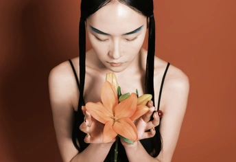一位留着橙色头发的年轻女子手里拿着一朵花