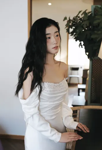 一位长发年轻女子穿着白色连衣裙摆姿势
