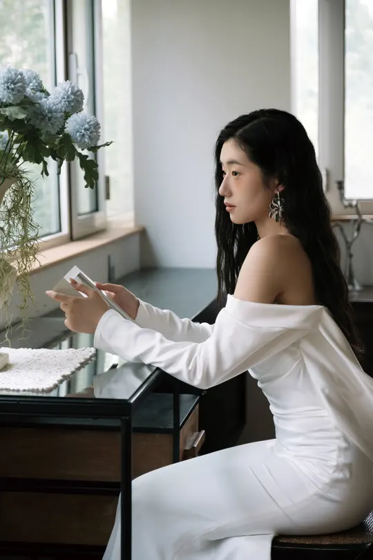 一个穿着长白色裙子的女人坐在桌子旁的椅子上