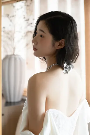 一位穿着白色婚纱的年轻女子正在镜子前照镜子