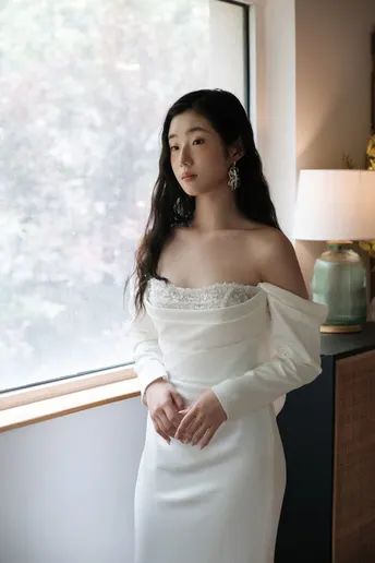 一位穿着白色连衣裙的女人站在窗前 扭过身去
