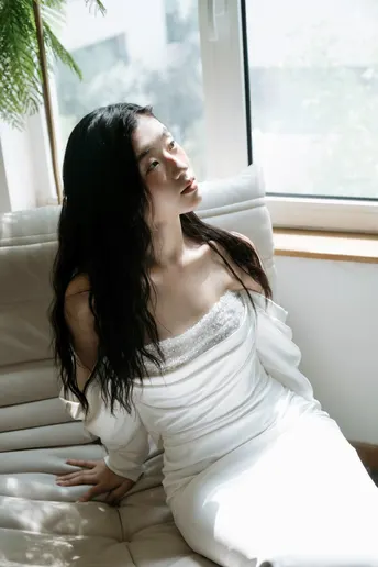 一个穿着白色连衣裙的女人坐在沙发上