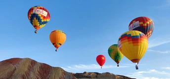 彩色的热气球在有山脉背景的峡谷上飞行。