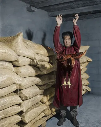 一个年轻男子站在仓库里 手里拿着装满米的袋子。