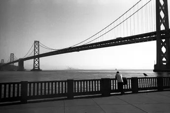 一对夫妇站在金门大桥的侧面 黑白照片。