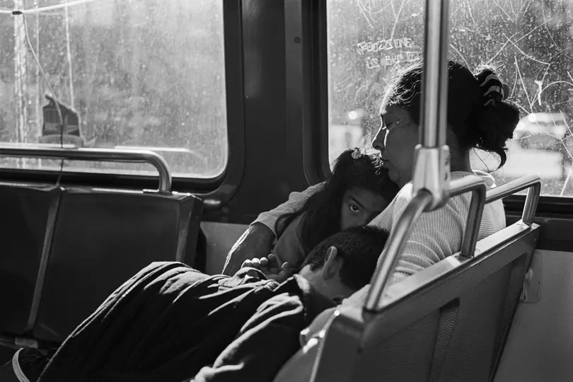 一个黑白照片 展示了一辆公交车上坐着一个男人和一个女人 他们坐在床上 一个孩子躺在床上 向外望着窗户