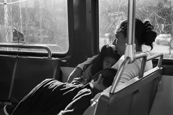 一个黑白照片 展示了一辆公交车上坐着一个男人和一个女人 他们坐在床上 一个孩子躺在床上 向外望着窗户